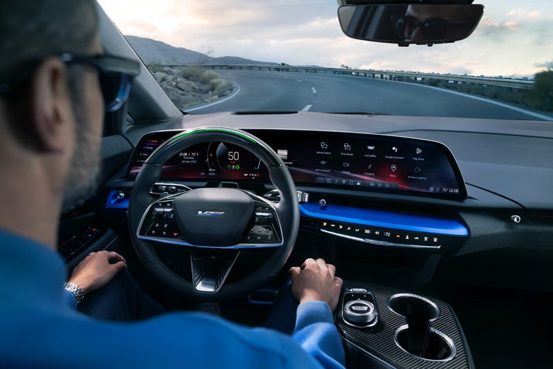 Front View of the 2026 OPTIQ-V Driving Through the Dusk Utilizing its Headlights | Cadillac of Billings in Billings MT