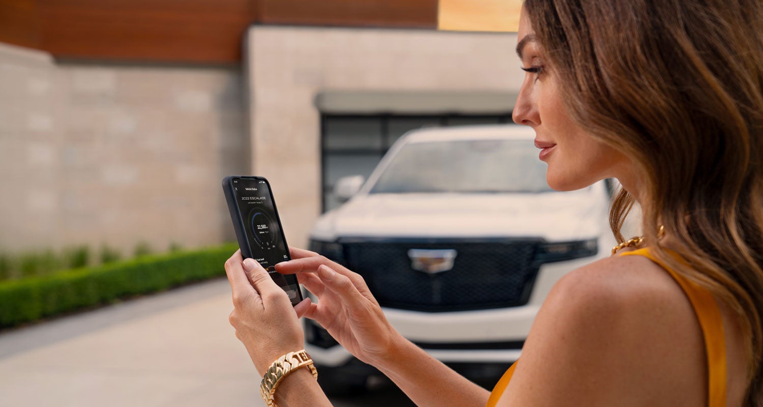 lady checking her mobile with a Cadillac vehicle background | Cadillac of Billings in Billings MT